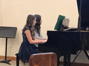 Two 7th and 8th grade students play a piano duet.
